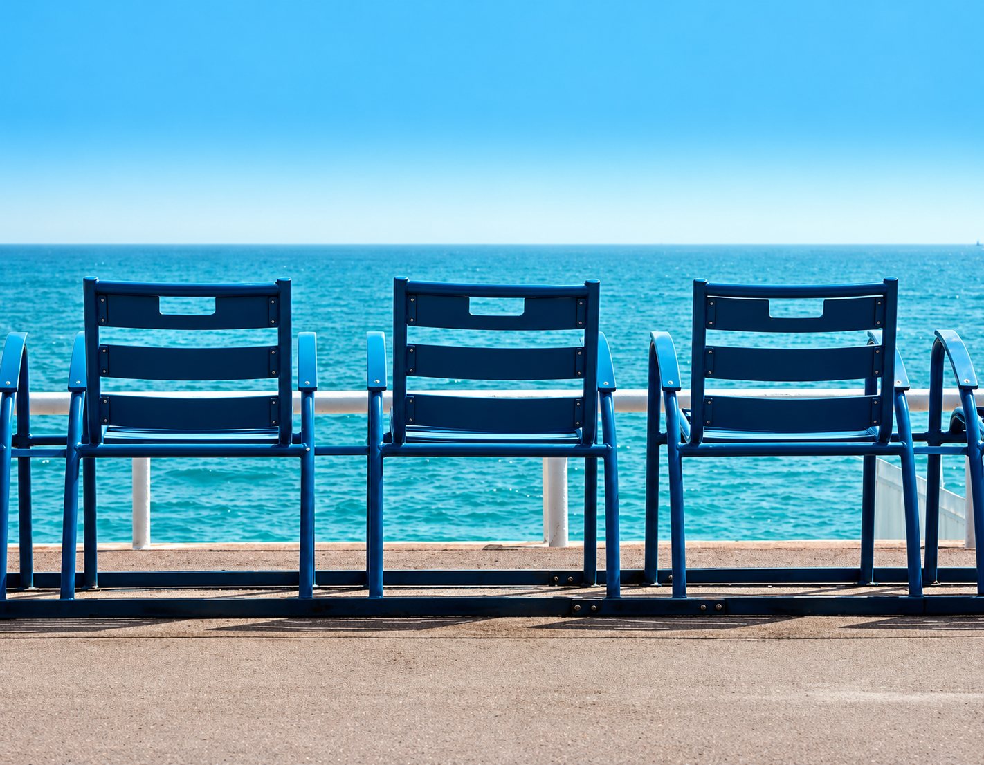Chaises bleues alignées face à la mer sur la promenade de Nice