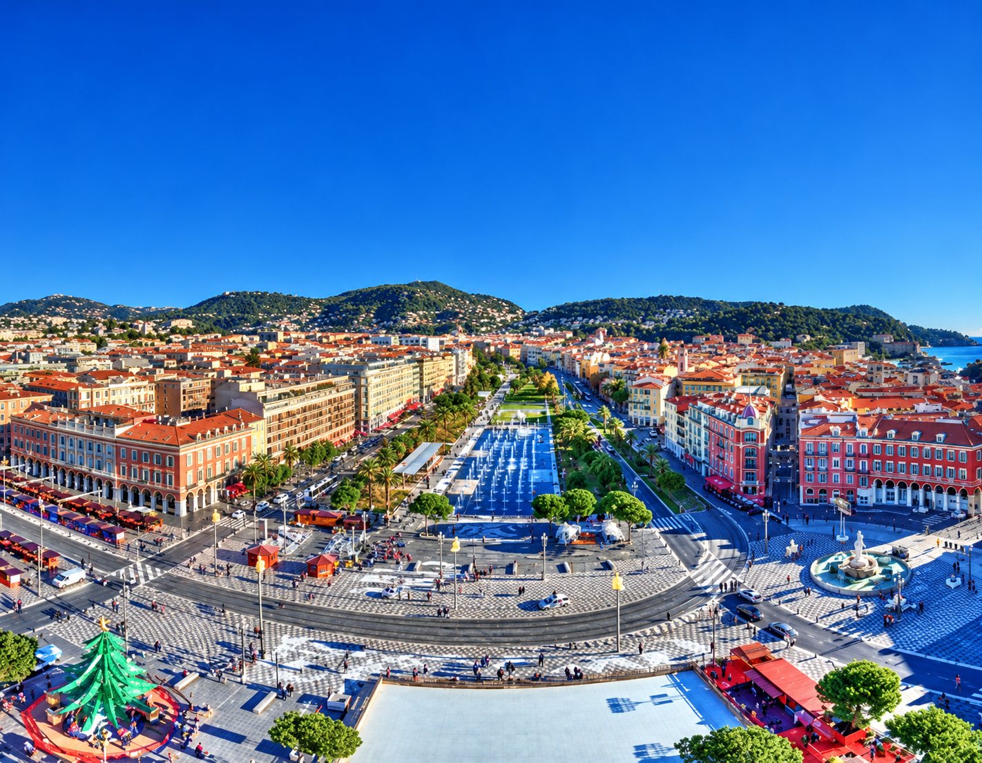 Vue aérienne du centre de Nice, avenue et place bordées d’immeubles ocre sous un ciel bleu