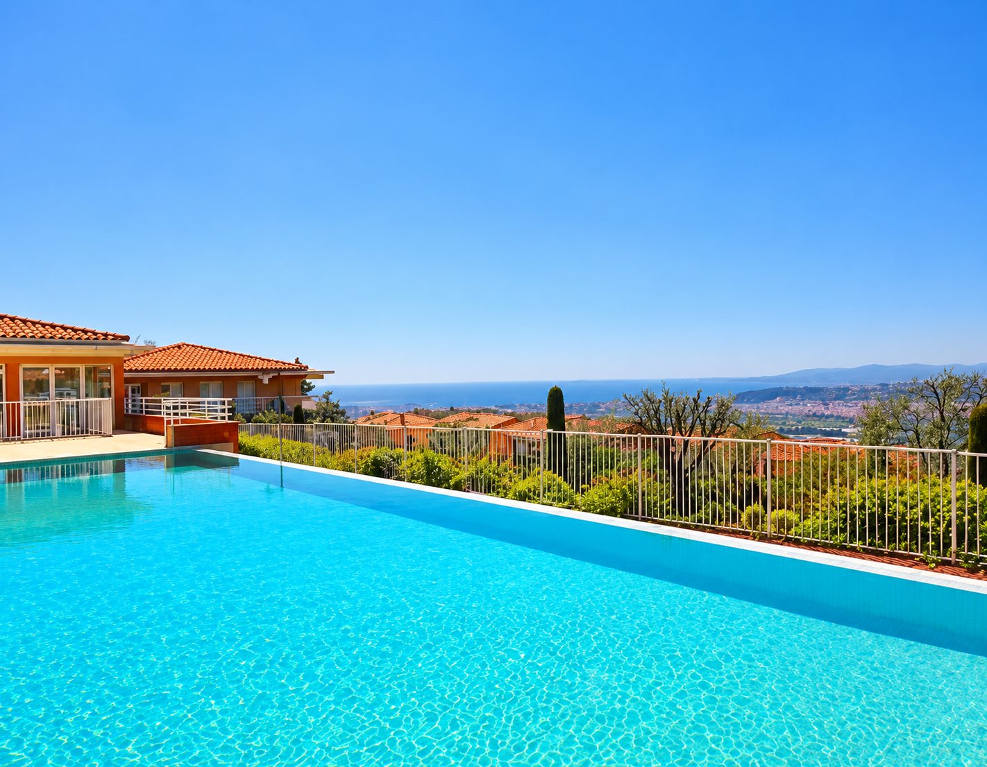 Piscine à débordement turquoise avec vue sur la mer et villa
