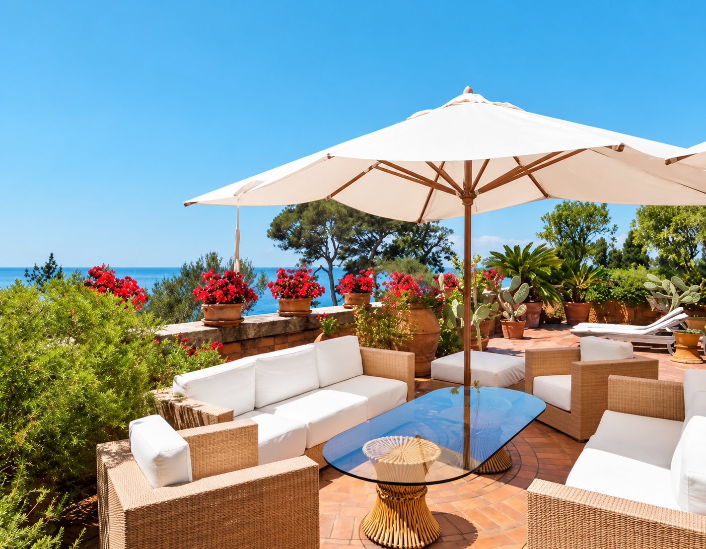 Terrasse ensoleillée avec salon blanc et parasol face à la mer
